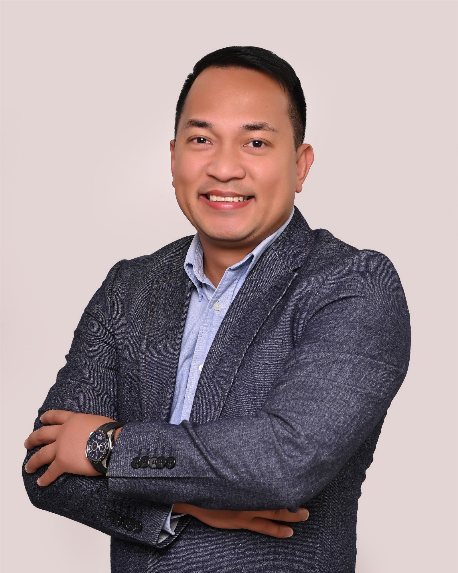 Jumar “Joms” Pando, founder of Purple Squirrel Cyber Security, smiling in a navy blazer and light blue shirt.